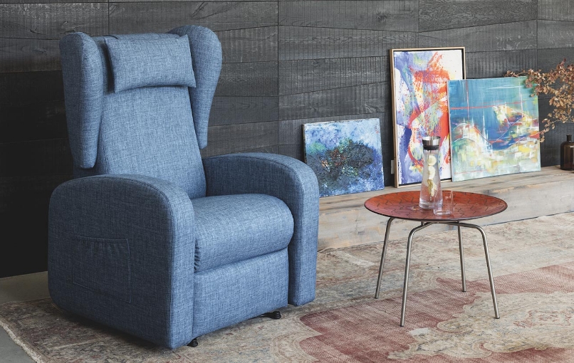 Aufstehsessel Mary in blauem Stoff in einem hellen Wohnraum